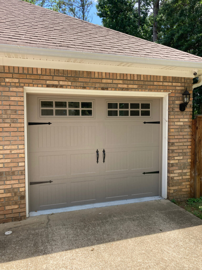 Garage door with square windows and black hinges. 