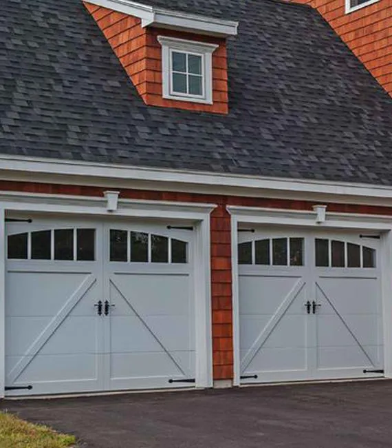 2 white barn-style garage doors with black handles and hinges 